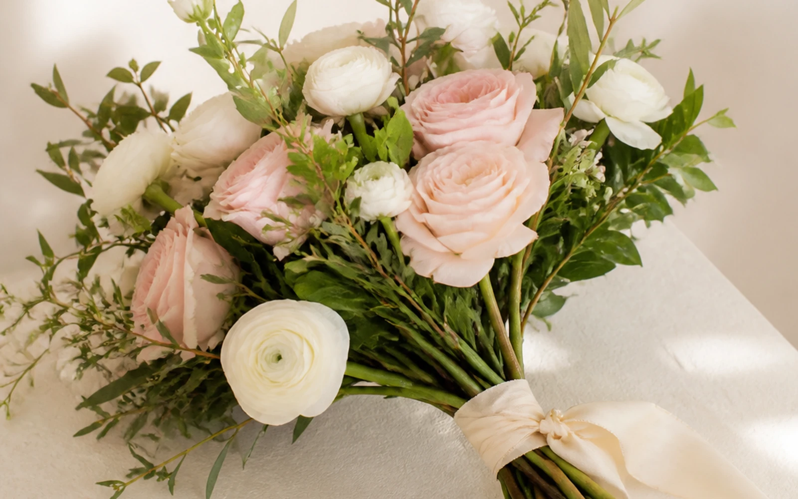 Hand-tied blush and ivory bouquet with exposed stems and restrained ribbon