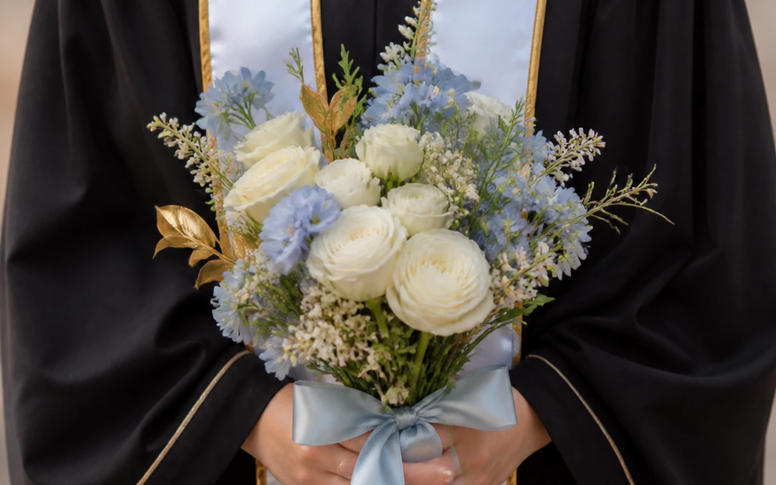 Graduate holding a compact bouquet below the chest for a portrait