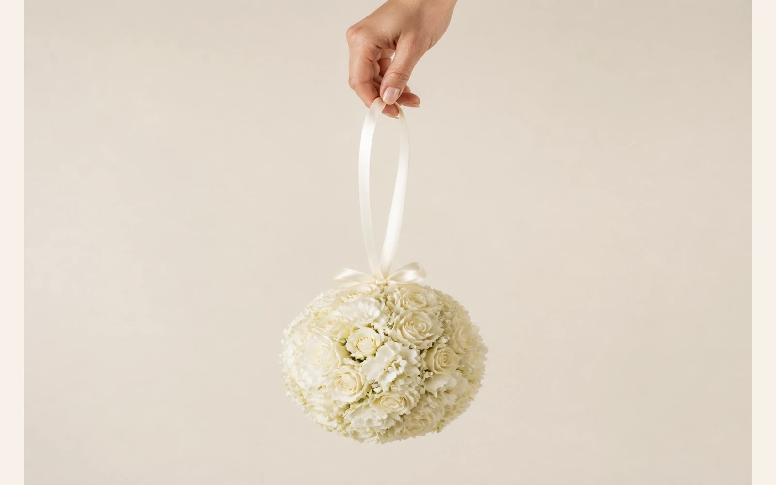 Pomander wedding bouquet shaped as a flower-covered sphere with a ribbon loop