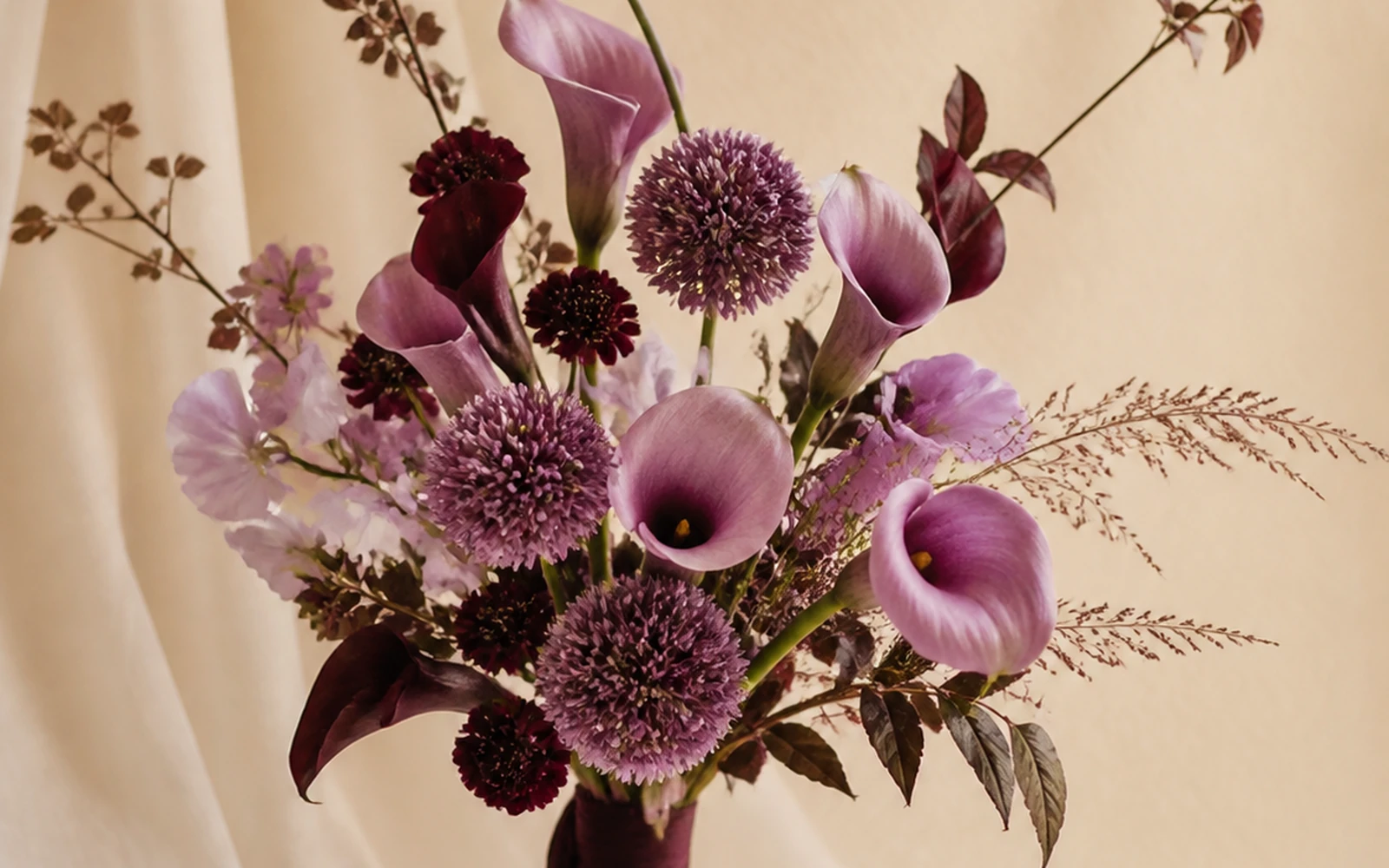 Plum architectural wedding bouquet with directional calla forms and spherical accents
