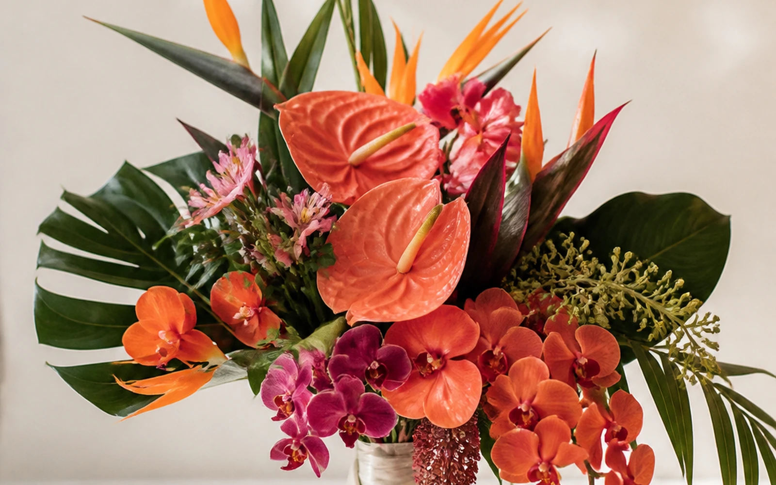 Tropical editorial wedding bouquet in coral, orange, magenta, and deep green